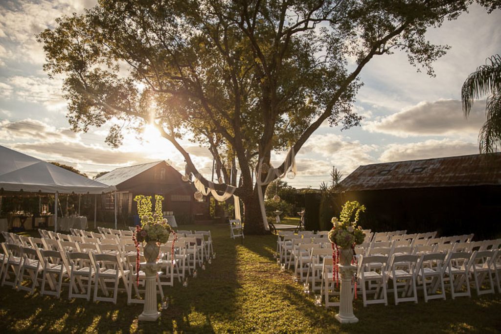 outdoor wedding venue with chairs in front of a tree at sunset