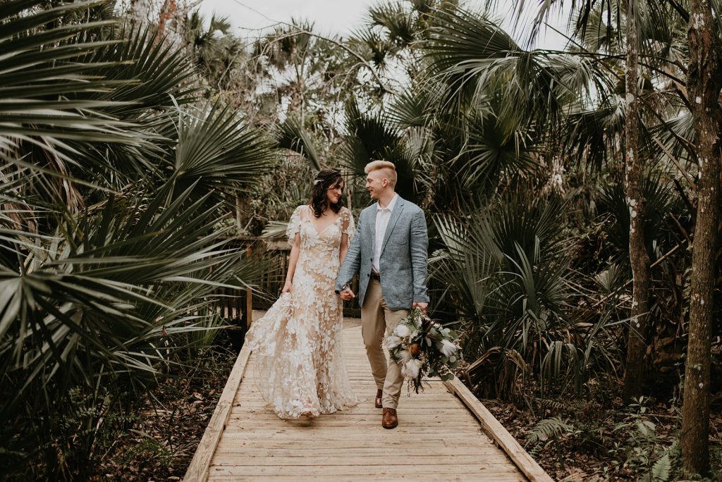 bride and groom walking through trees